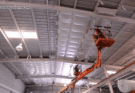 Worker insulating the walls of an existing metal building with spray foam for better energy efficiency