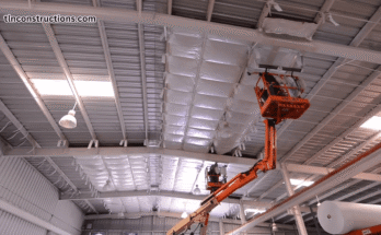 Worker insulating the walls of an existing metal building with spray foam for better energy efficiency