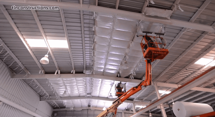 Worker insulating the walls of an existing metal building with spray foam for better energy efficiency
